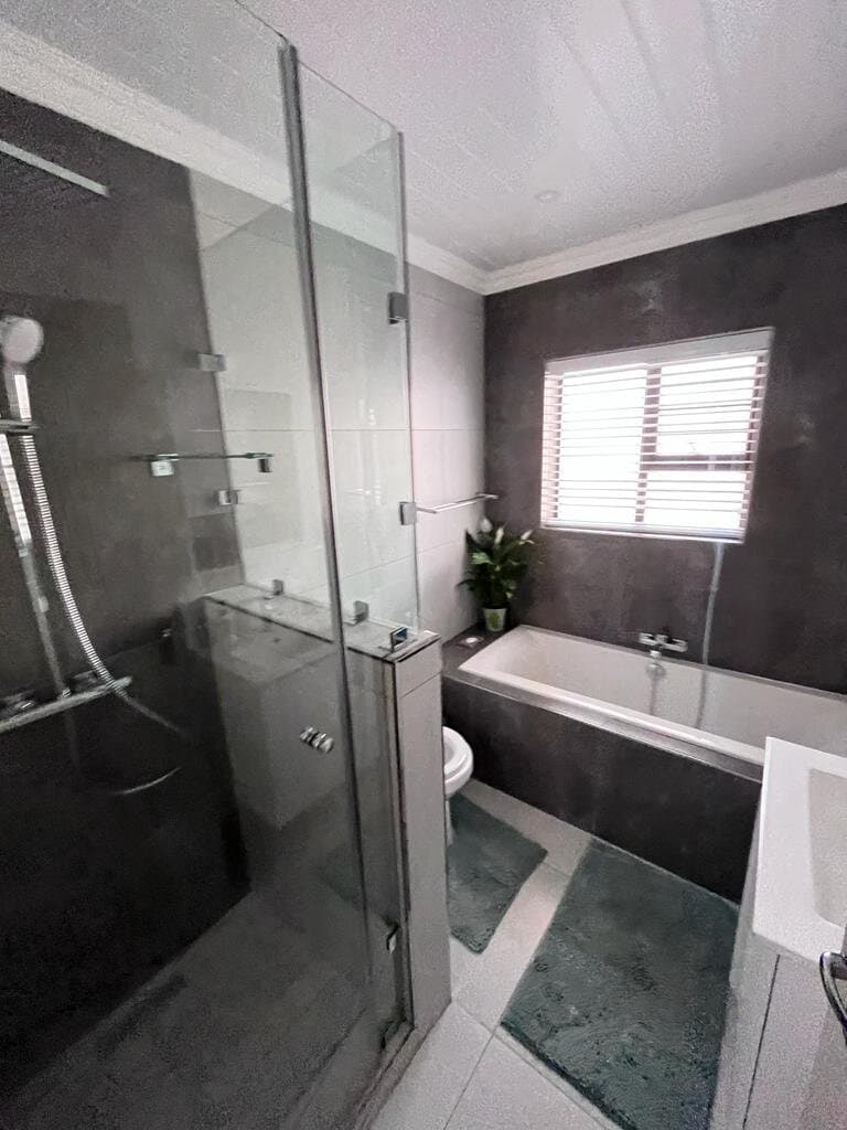 Bathroom renovation with a built-in bath, dark tiled feature wall and shower enclosure