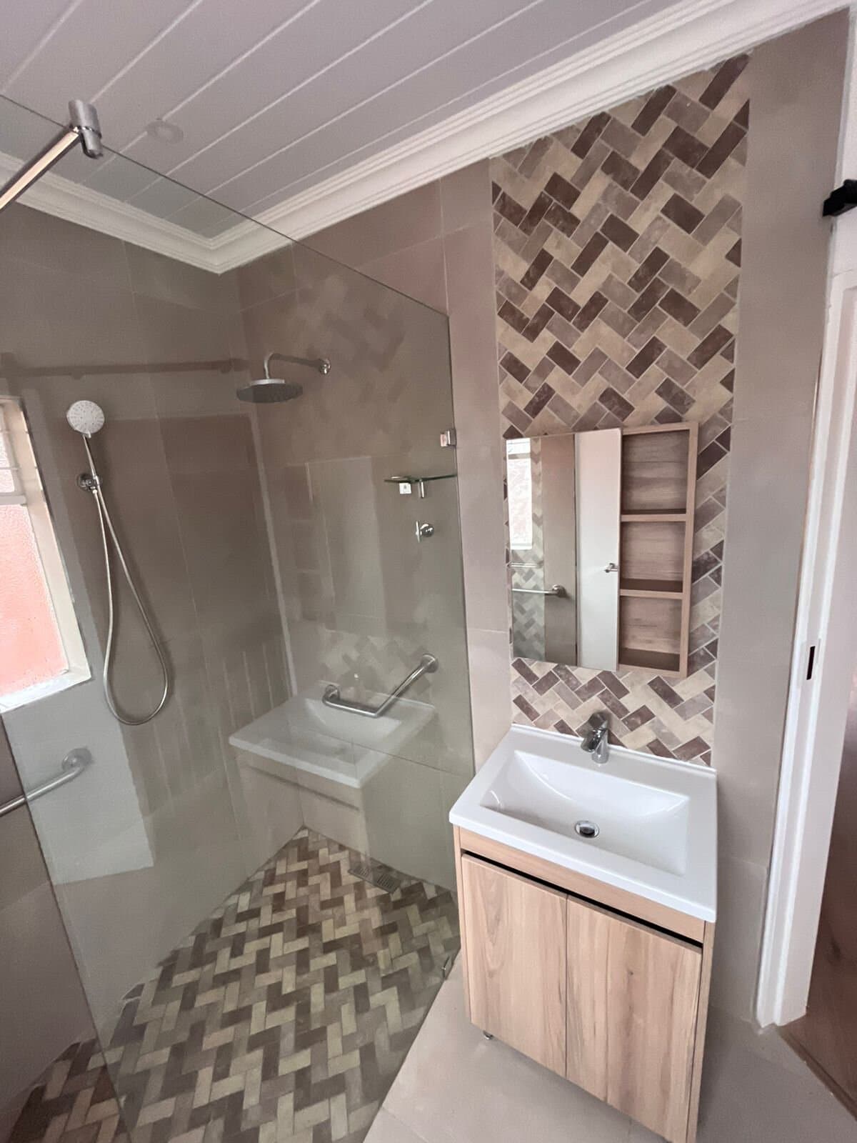 Bathroom renovation with a herringbone tile feature wall, walk-in shower and vanity