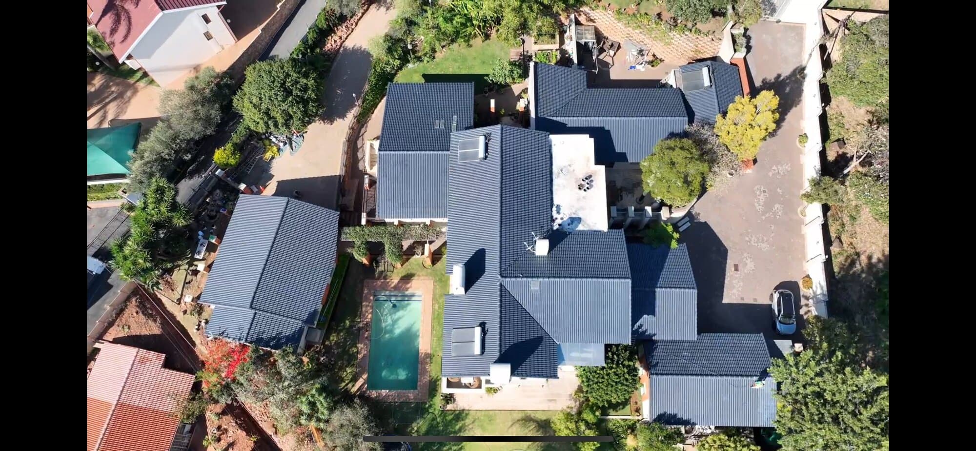 Aerial drone view of a renovated property showing the roof, pool and outdoor entertainment area