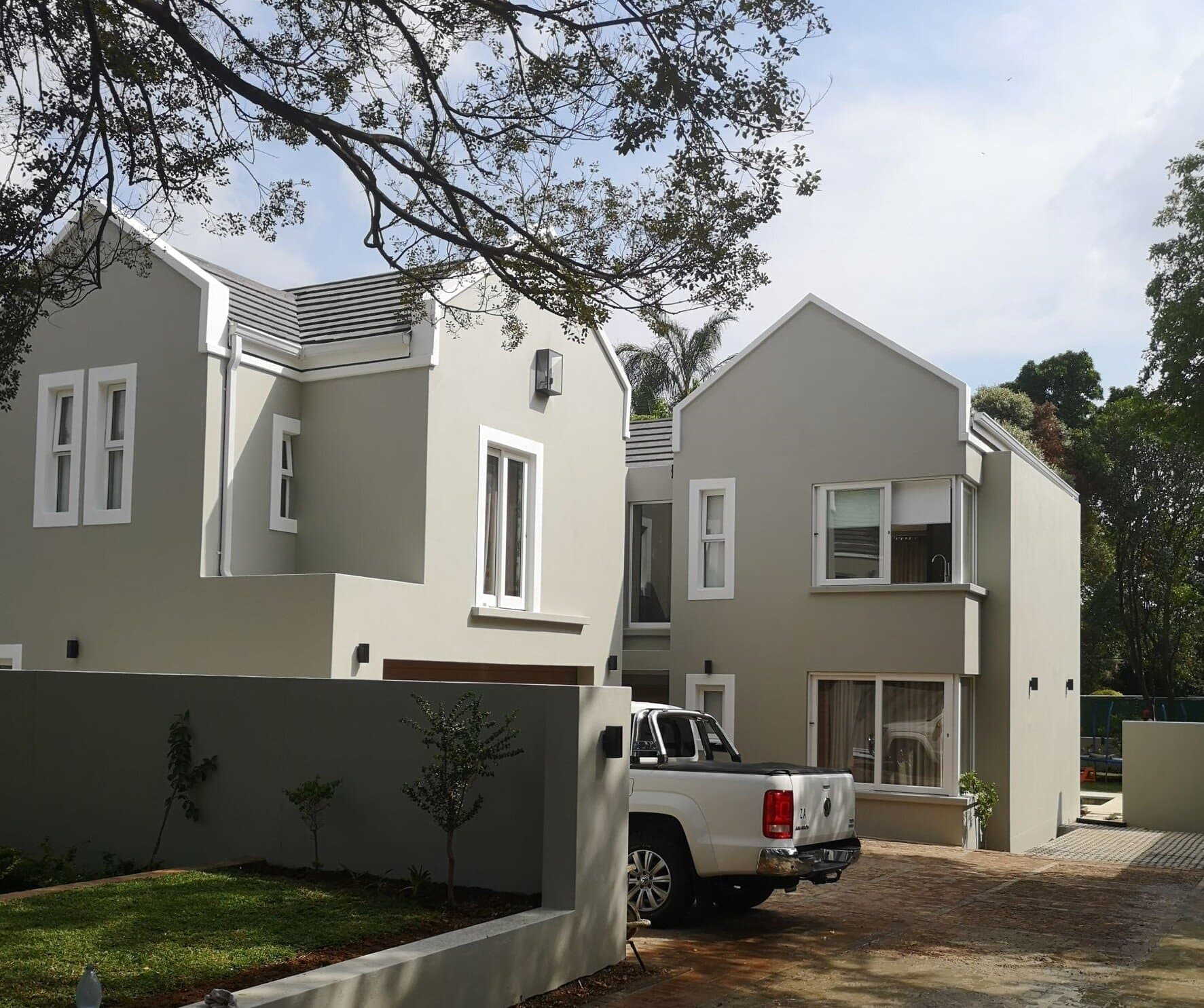 Freshly painted double-storey home exterior with grey render and white window trims