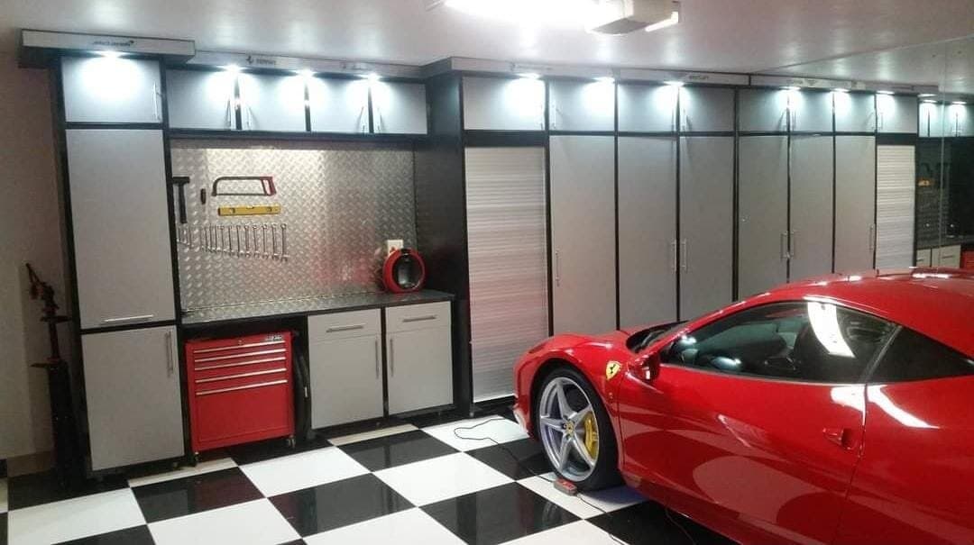 Garage fit-out with black and grey cabinetry, tool storage wall and checkerboard flooring