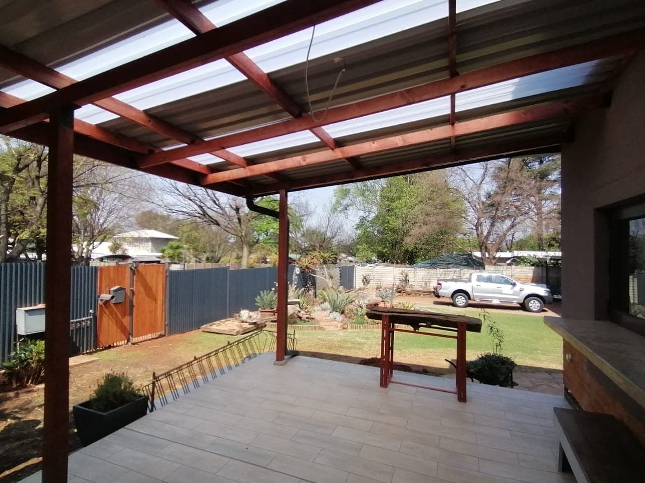 Timber pergola patio under construction with a paved deck and built-in braai