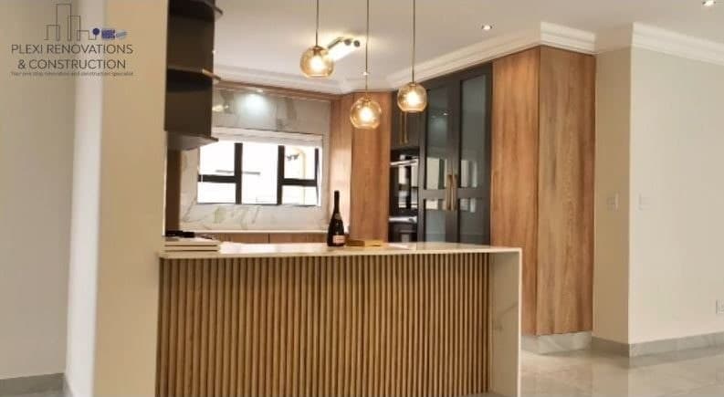 Renovated kitchen with slatted wood island, oak cabinetry and pendant lighting